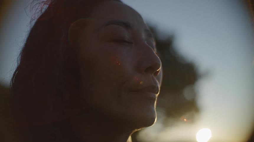 Portrait of a woman with closed eyes in a natural environment with sunlight reflecting on her face