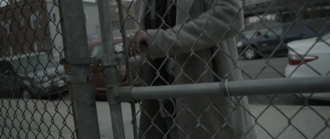 A woman walks through a gate and then locks it