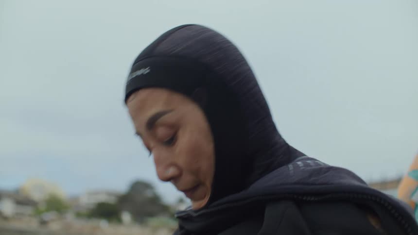 Woman adjusting her wetsuit on a cloudy day