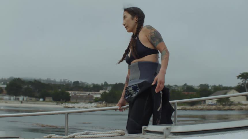 Scuba diver on a boat stretching her legs on a cloudy day