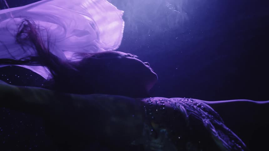 A woman is swimming to the surface of the water