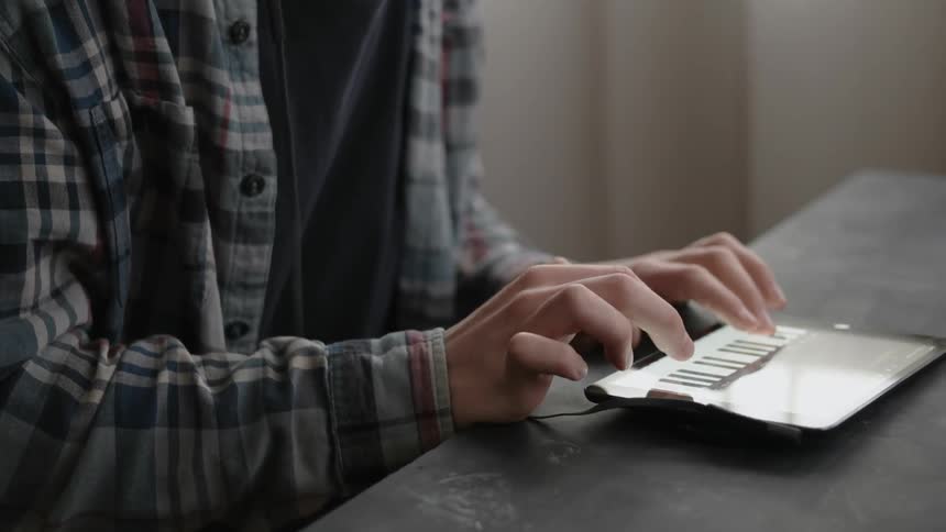 A man plays a digital keyboard on a tablet