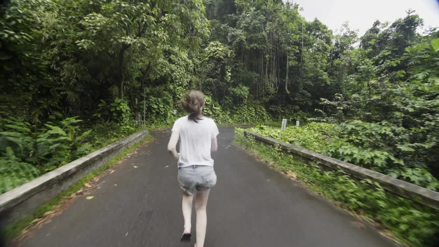 A woman runs down a path in a forest