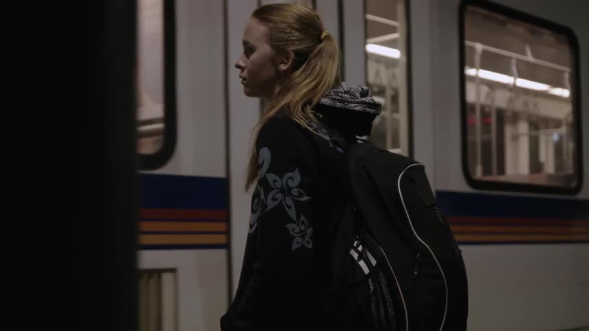 A woman stands watching a train pass by