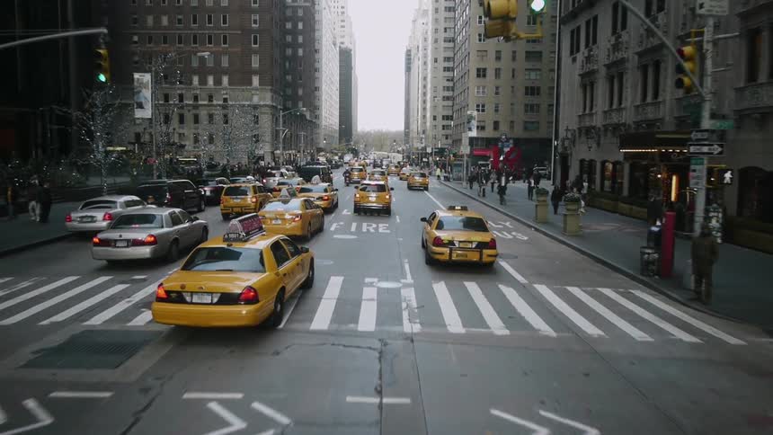 A bunch of taxis race down a city street