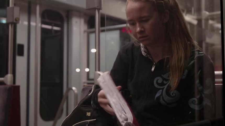 A woman looks through her bag on transit