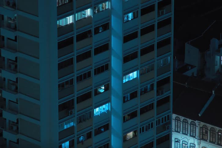 Exterior view of tall buildings with flickering lights during night in the city