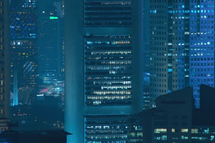 The exterior view captures office buildings in the city at night with lights flickering highlighting the bustling and dynamic nature of urban workspaces