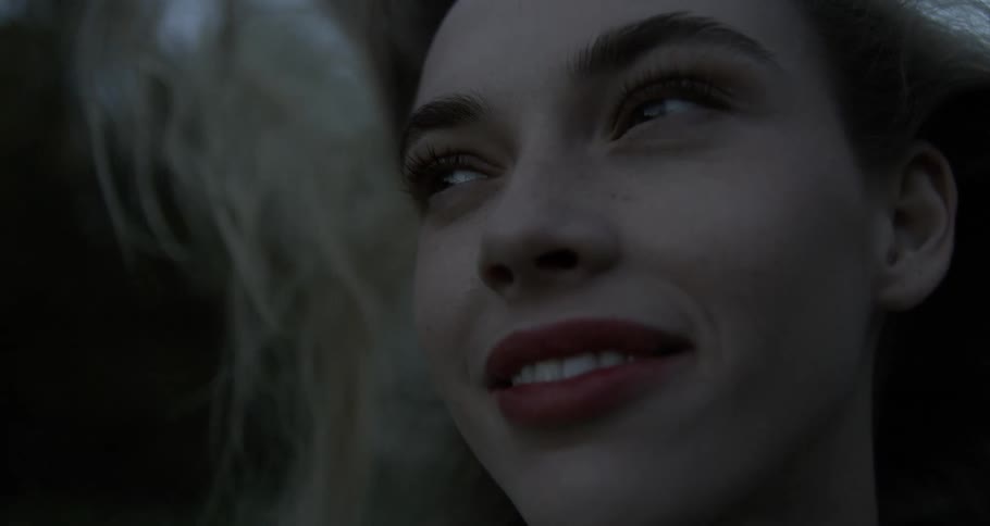 Portrait of a blonde woman with lipstick giving a smile and her hair flying