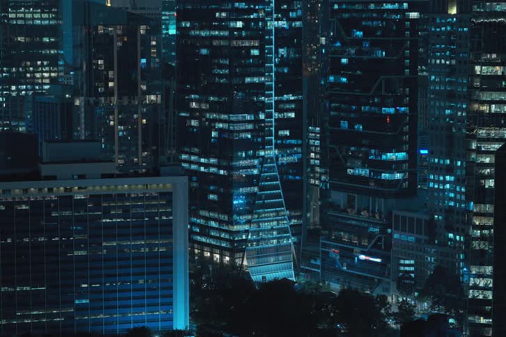 Exterior view of condos in the city at night with lights flickering painting a vibrant and urban scene