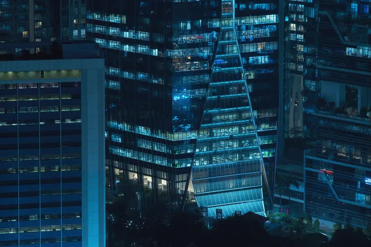 Blue reflected lights turning on and off through building windows in the city at night