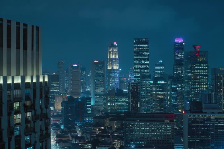 The exterior view captures tall buildings and skyscrapers in the city at night with lights flickering painting a vibrant and urban scene