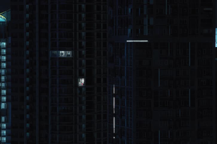 Blue reflected lights turn off then go dark in windows of skyscraper in the city at night