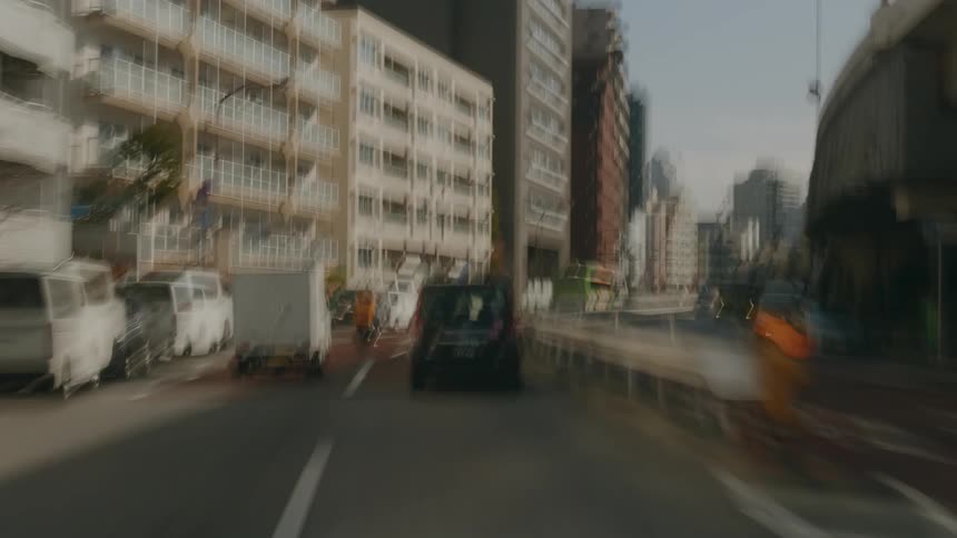 A black car driving on a street with some other cars in a city