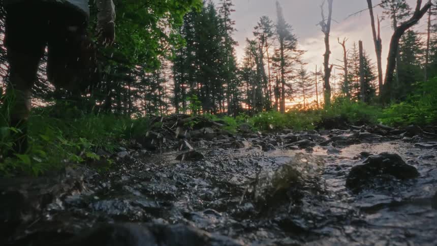 Man running in nature stepping on grass rocks and water with his back turned in the morning