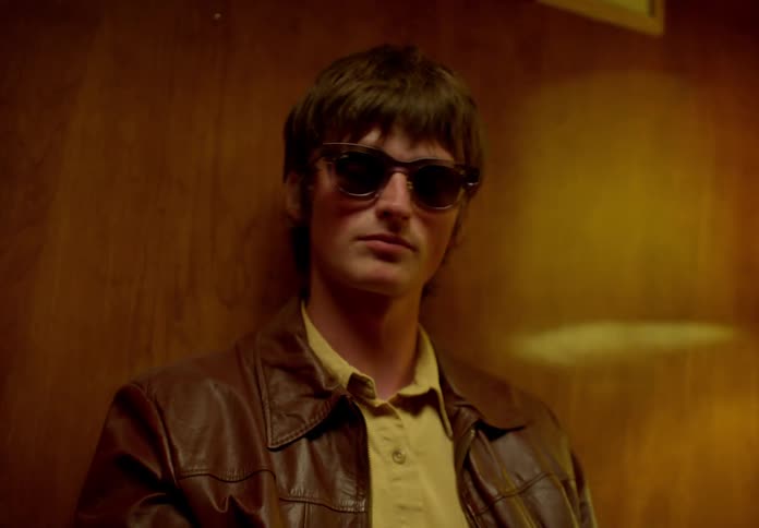 Man sitting in a chair in the room and putting on his sunglasses