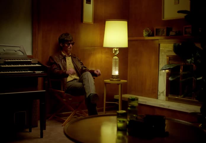 A man sits down and puts on sunglasses