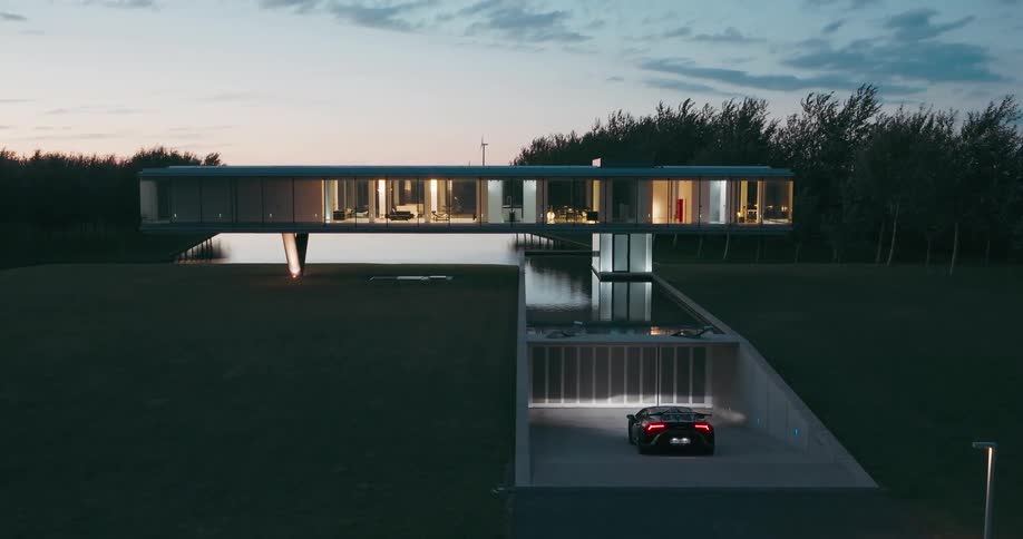Exterior architecture of a mansion in a natural setting with a driveway leading to the gate under a morning sky