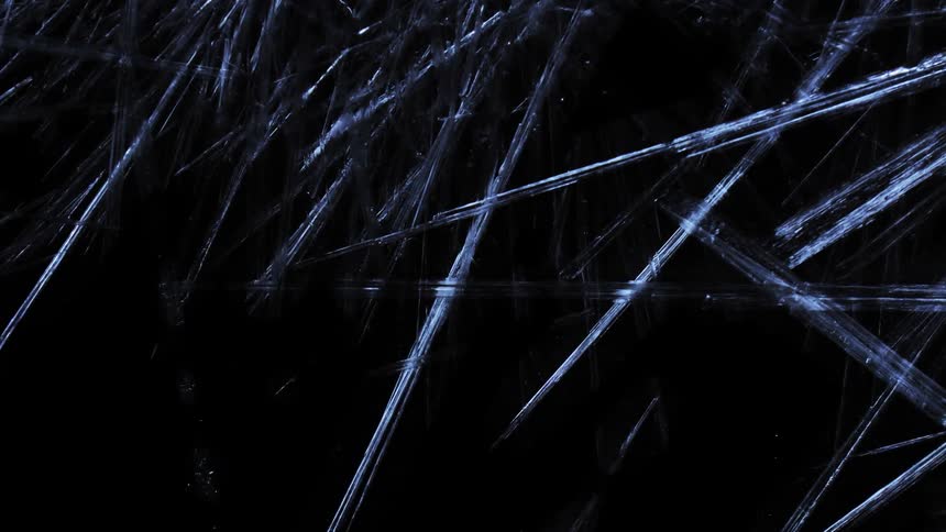 Shards of light blue frozen ice form against a dark background