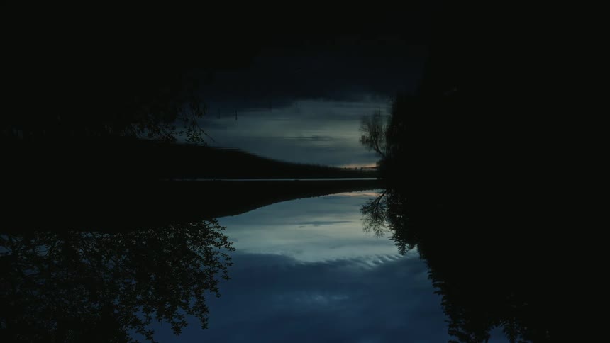 View of a reflective lake with a dark dawn sky