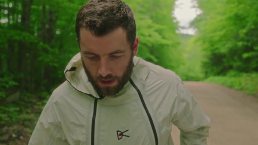 A bearded man is jogging on a forest road