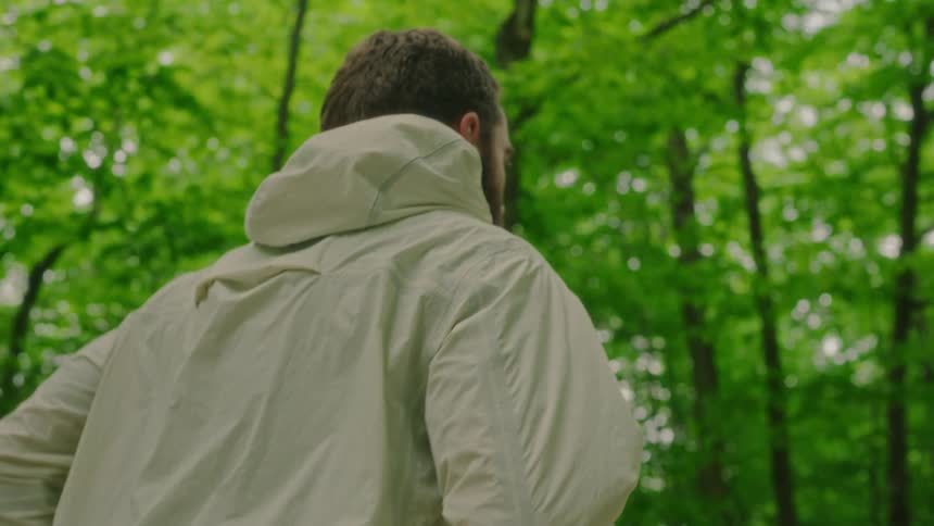 A man is jogging through a forest