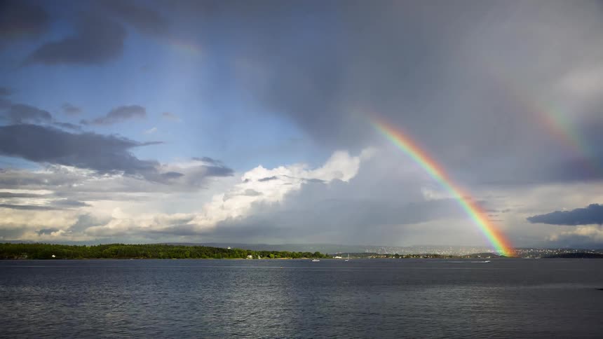 A rainbow crossing the sky reflecting in the seawater
