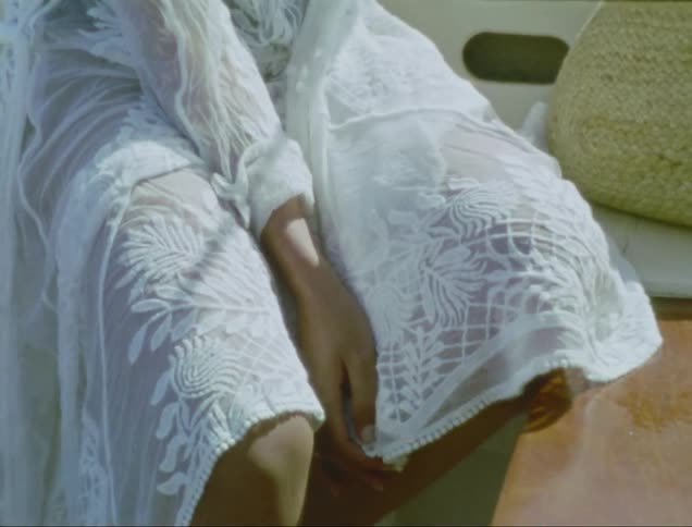 Female wearing embroidered dress sits outdoors on windy day