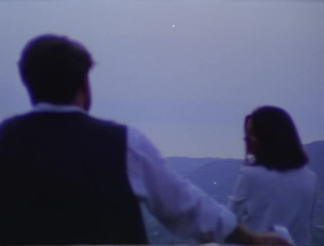 Back view of a man and a woman talking while standing outdoor at sunset