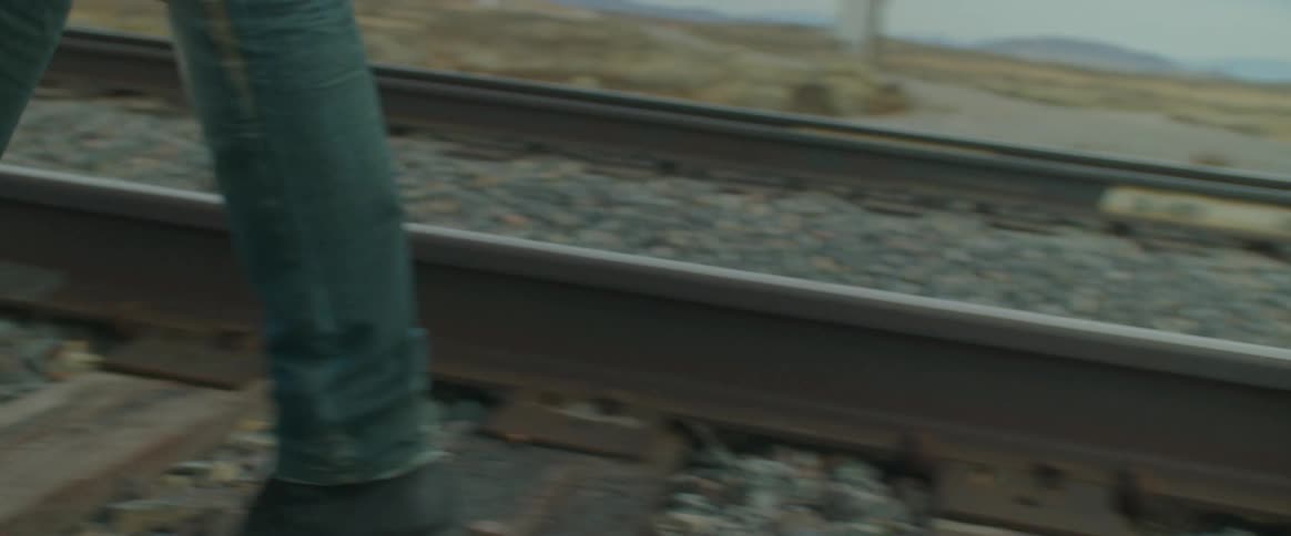 View of a mans legs walking in the middle of the railway tracks