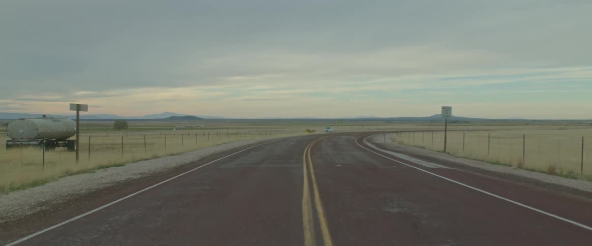 Flat grassland with a road in between them in a desolate area