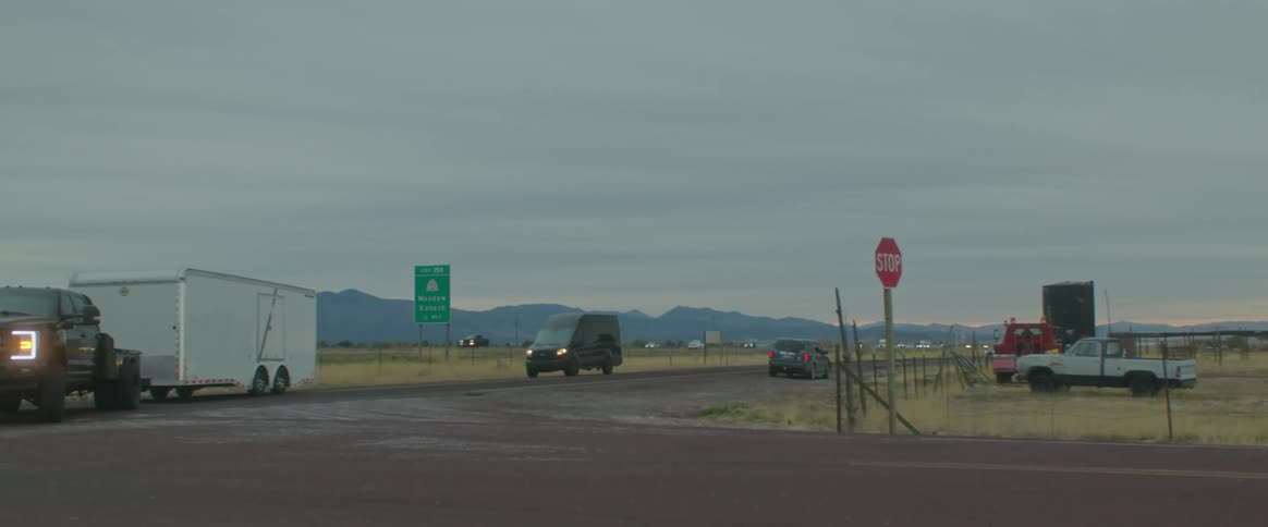 A truck pulling a horse trailer turns off the highway onto another road at dusk