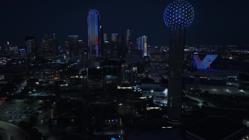 City skyline lit up at night with lights around a large sphere