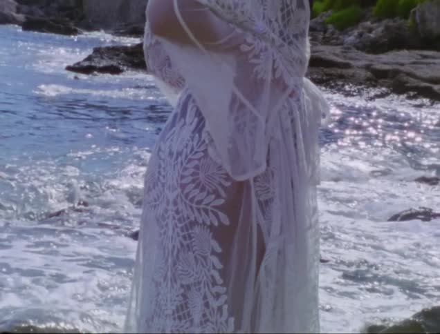 Young woman models a white gown on the beach