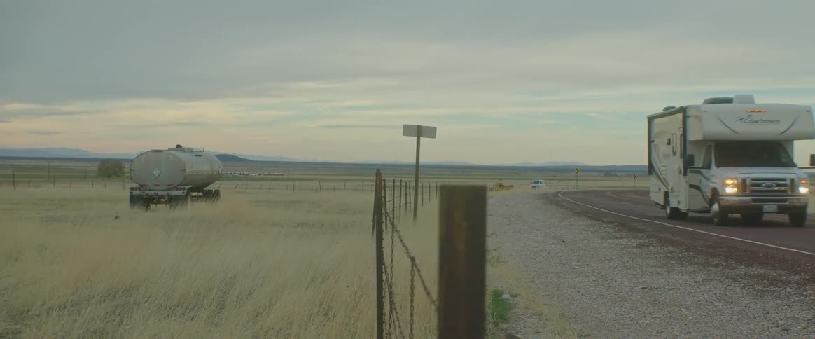 A trailer driving along the deserted road in a pasture field