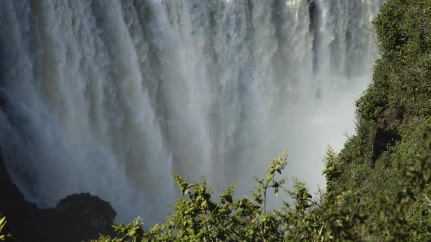 A vast waterfall pours down a cliffside on a sunny summer day