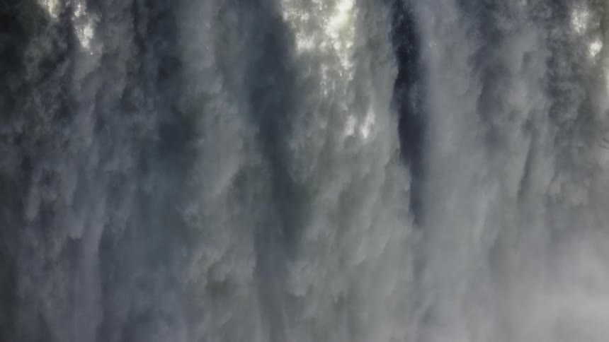 A large misty waterfall hit by sun rays