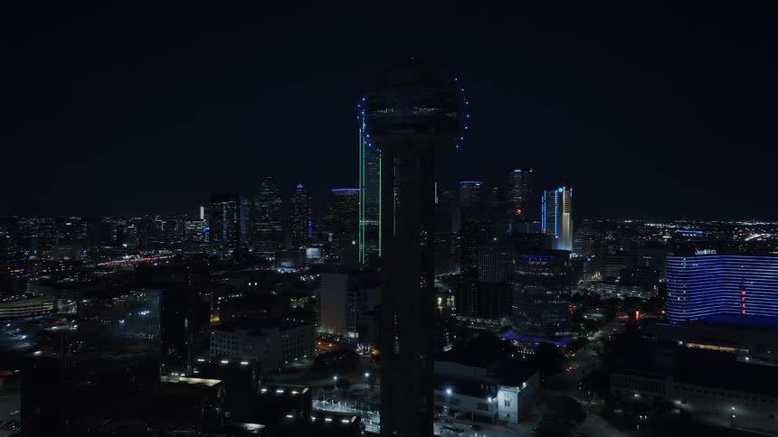 A tower with a sphere with glowing lights at the top of the city