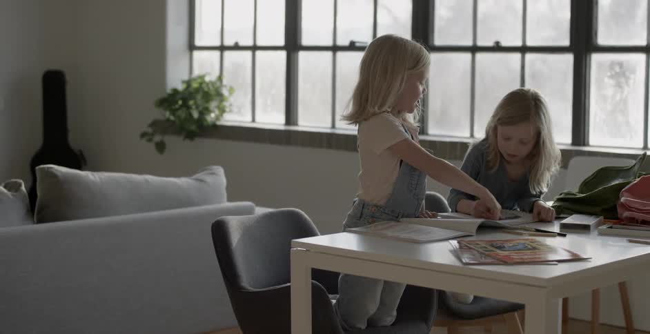 Two girls color at a table