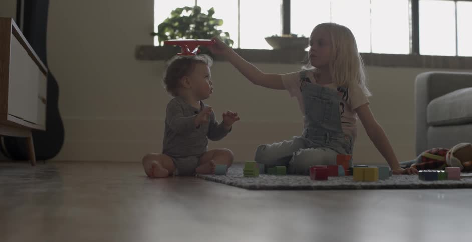 Two children play with toys on a rug on the floor