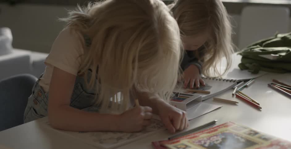 Two girls color at a table