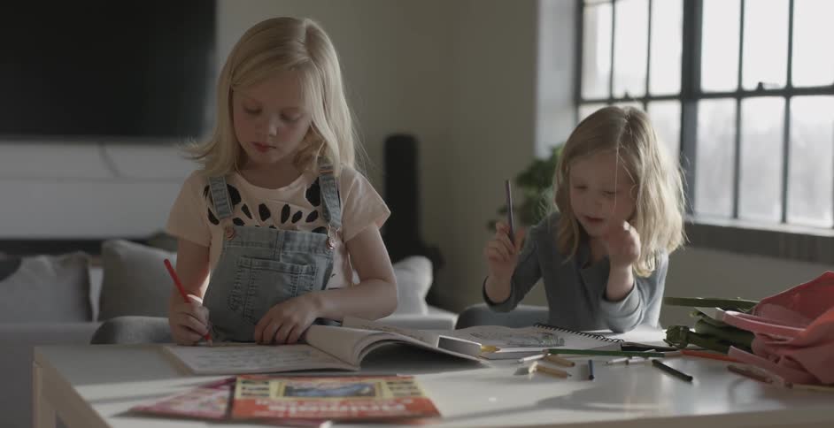 Two girls are drawing sitting at a table