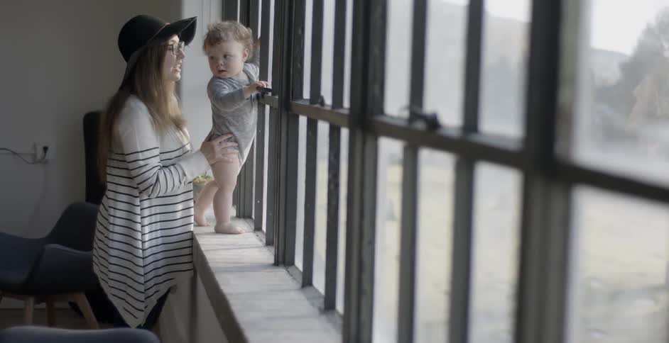 A woman holds her baby by the window