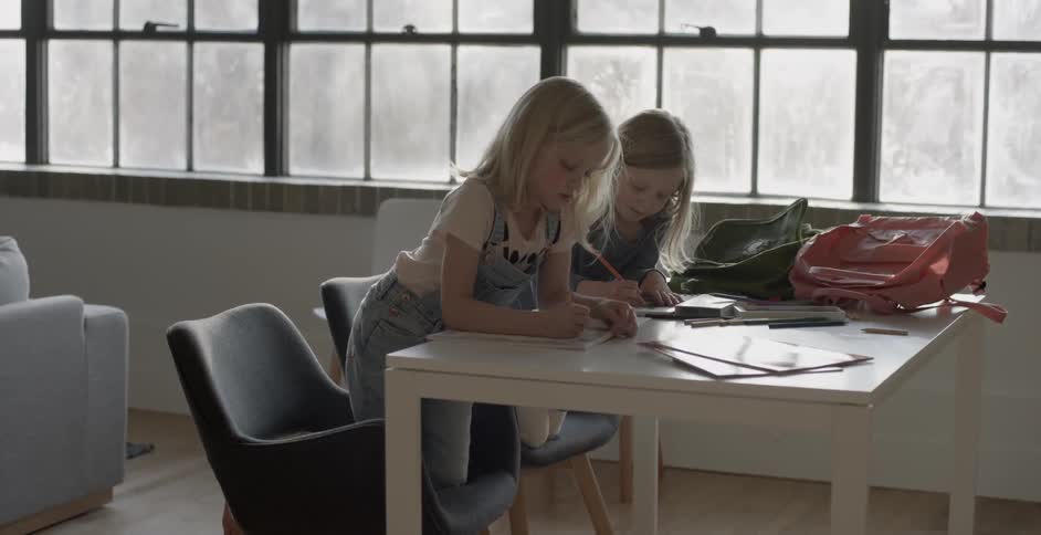 Two children are at a table drawing