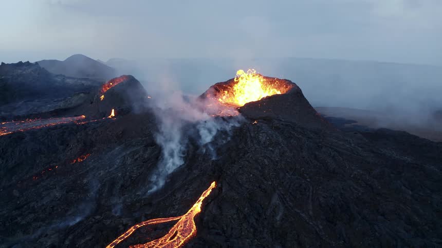 Erupting volcano with splashing lava and white smoke