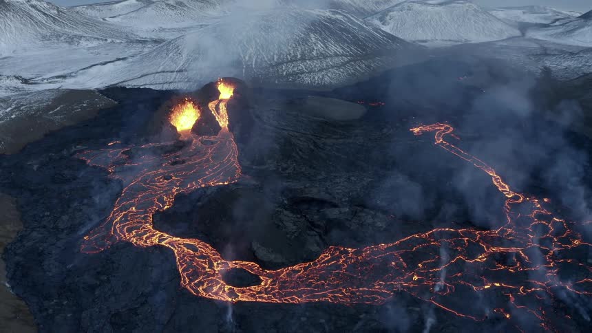Aerial of a black charred icelandic volcano erupting gold lava into flowing streams