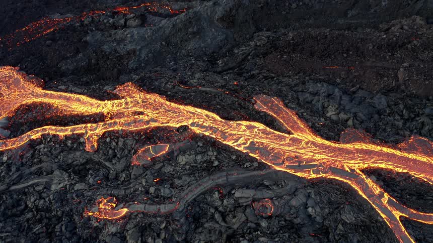 River of lava flows through ash covered terrain