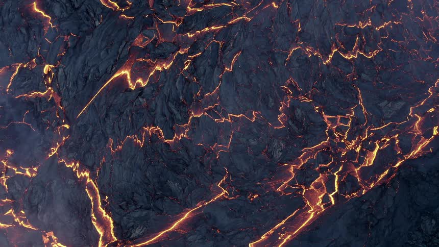 Molten hot lava glows in the darkness as it flows from an erupting volcano