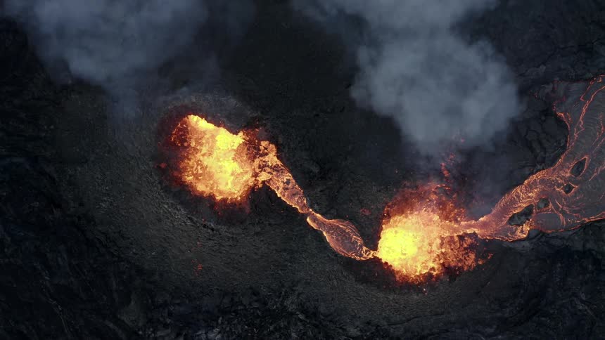 From the sky a volcano erupting with billowing smoke and molten lava spewing out
