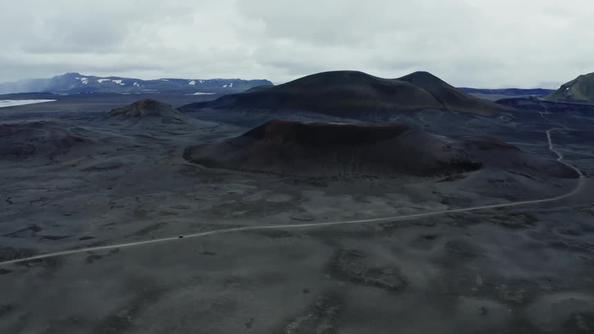 Car drives on a road in a black desert
